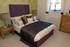 Soft greens and aubergine create impact in the master bedroom